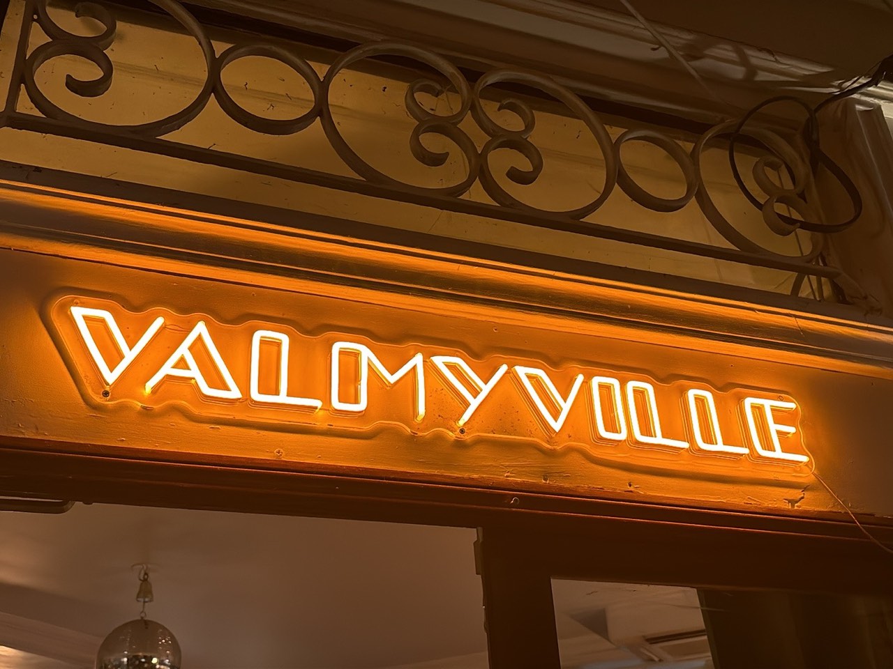 L’enseigne néon Valmyville allumée au-dessus de la porte, la boule à facettes visible en dessous